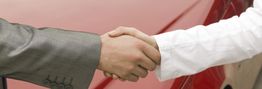 Zwei Personen schütteln sich die Hand, eine im Anzug, die andere in Weiß gekleidet.