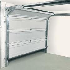 White sectional garage door partially open in a light grey garage space.