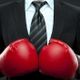 Man in suit with red boxing gloves, symbolizing business competition or challenge.