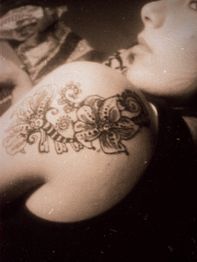 Nahaufnahme eines Schmetterlings- und Blumen-Tattoos auf der Schulter einer Person.