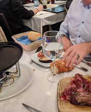 Personas en un restaurante con carne cruda y vino sobre la mesa.
