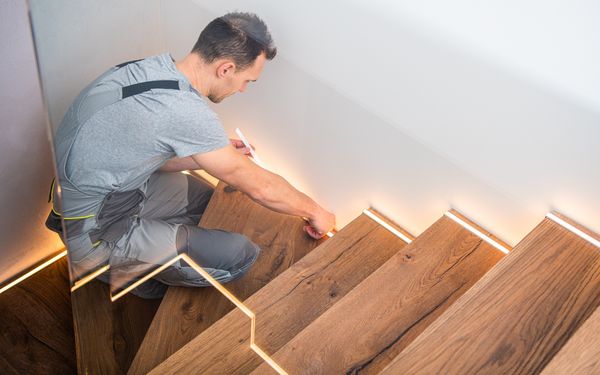 Ein Handwerker vermesst eine Holztreppe zur Reparatur.