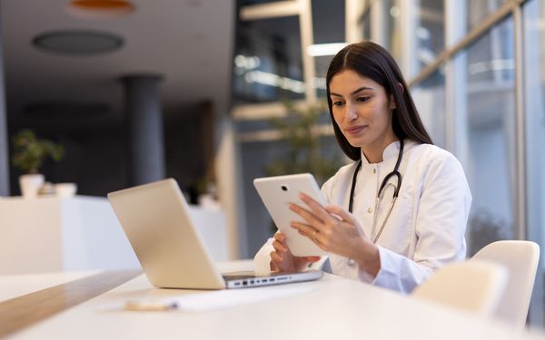 Eine Ärztin kommuniziert über ein Tablet mit ihren Patienten.