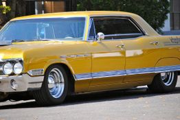 Gelbes Oldtimer-Auto, geparkt auf der Straße, mit glänzenden Chromakzenten und Retro-Design.