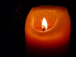 Kerze mit brennender Flamme in der Dunkelheit.