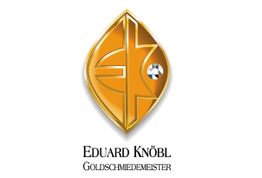 Goldenes Logo mit stilisiertem Emblem und funkelndem Diamant, darunter der Text "Eduard Knöbl".