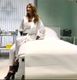 Donna seduta su un lettino medico in una stanza luminosa e sobria, indossa abbigliamento bianco.