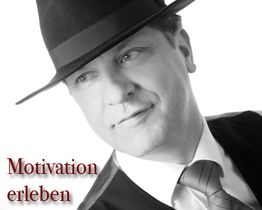 Mann mit Hut und Anzug lächelt; Text lautet: "Motivation erleben".