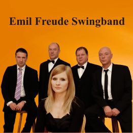 Eine Frau und vier Männer in Anzügen vor orangem Hintergrund mit Schriftzug „Emil Freude Swingband“.