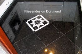 Schwarzer Fliesenboden mit weißem Sternmuster, Schrift: Fliesendesign Dortmund.