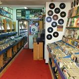 Platenwinkel met vinylplaten aan de muur en rekken vol lp's aan weerszijden, rode vloer.
