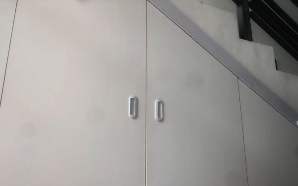 Ein weißer Einbauschrank eingebaut unter der Schräge einer Treppe.