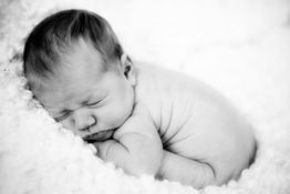 Schlafendes Baby, eingekuschelt in weiche Decke, schwarz-weiß Aufnahme.