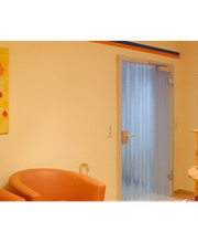 Zwei braune Stühle in einem Wartezimmer, daneben ein gelbes Bild mit roten Blumen an der Wand.