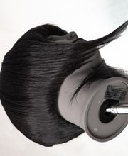 Testa di manichino con capelli scuri lisci su supporto metallico, vista laterale.