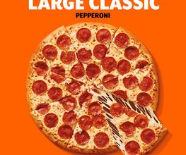 Pizza grande de pepperoni con queso derretido sobre fondo naranja brillante.