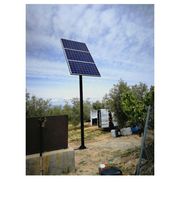 Panel solar elevado en un área rural, con cielo despejado y vegetación alrededor.