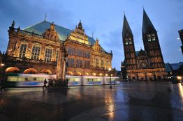 Historische Gebäude und eine Bahn bei Dämmerung auf einem Platz in Bremen.