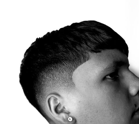 Profilo di un ragazzo con orecchino e capelli corti, sfondo bianco.