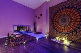 Habitación con decoración bohemia, alfombra mandala y velas encendidas en un ambiente relajado.