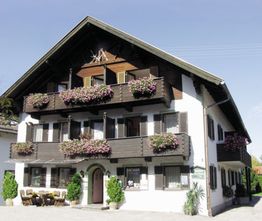 Ein traditionelles Haus mit Holzbalkonen, geschmückt mit bunten Blumen, bei sonnigem Wetter.