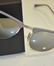 Gafas de sol plateadas sobre una caja negra, reflejando luces en los cristales.