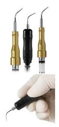 Dental ultrasonic scaler tips, gold and black, with a gloved hand holding one.