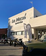 Edificio con letrero "La Masó Sports Club" y varias motos estacionadas al frente.