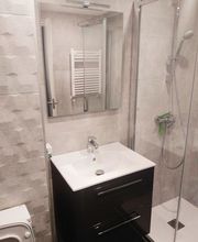 Baño moderno con ducha, lavabo, espejo y paredes decoradas en tonos grises.