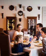Familia disfrutando de una comida en un restaurante elegante con decoración en las paredes.