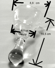 Transparentes Glas auf Tisch, Breitenmaße: 8,8 cm, 6,5 cm, Länge: 15,5 cm, mit schwarzen Pfeilen.