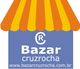 Logotipo do Bazar Cruzrocha com uma fachada de listras amarelas e laranjas.