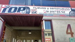 Entrada de un taller de neumáticos con cartel promocionando precios y servicios en la fachada.