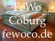 Grünes Schlafzimmer mit Doppelbett, farbigem Bettzeug, Schriftzug: "FeWo Coburg fewoco.de".
