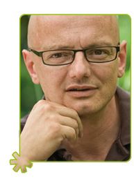 Eine Person mit Brille, stützt das Kinn auf die Hand, grüner Hintergrund.