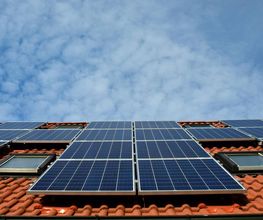 Techo con paneles solares bajo cielo azul con nubes.