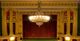 Opulent theater interior with a grand chandelier and red curtain stage.
