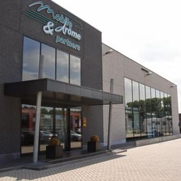 Grijs gebouw met grote ramen en het logo "Mobile & Drome Partners" op de gevel.