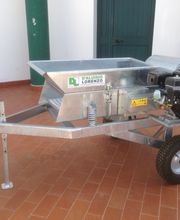 Macchina agricola su ruote con motore, su pavimento in piastrelle, vicino a una porta e colonne verdi.