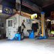 Autogarage-interieur met gereedschap, hefbrug en banden tegen de muur.