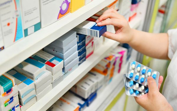 Apotheker sortiert Blister in Apothekerschrank.
