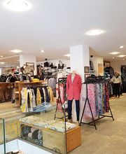 Kleidungsgeschäft mit Kleiderständern, Regalen und Jacken auf einem Mannequin.