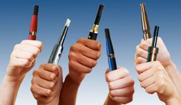 Mehrere Hände halten farbige E-Zigaretten vor blauem Himmel hoch.