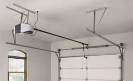 Garage door opener installed on the ceiling with metal tracks and a closed door.