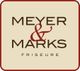 Logo mit der Aufschrift "Meyer & Marks Friseure" auf beigem Hintergrund mit rotem Rahmen.