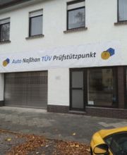 Geschäftsgebäude mit Schild "Auto Najjhon TÜV Prüfstützpunkt", geparktem gelben Auto davor.