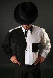 Ein Mann im schwarz-weißen Hemd, Hut verdeckt sein Gesicht. Schwarzer Hintergrund.