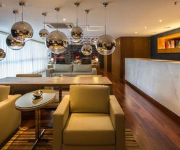 Sala moderna com poltronas, balcão e luminárias esféricas. Decoração elegante e sofisticada.