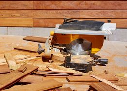 Wood saw with scattered planks, surrounded by wood shavings.