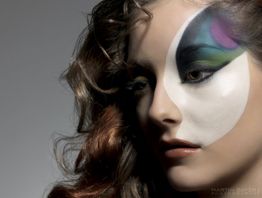 Frau mit kunstvollem Make-up in Schwarz-Weiß auf dem Gesicht, Haar offen.